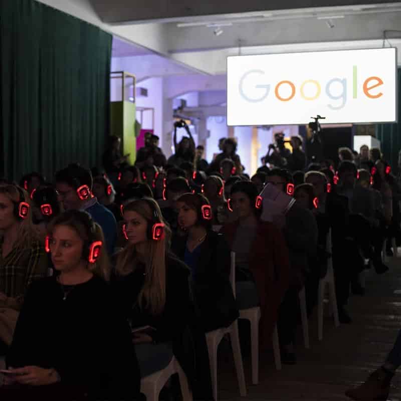 Silent Meeting Google Audience wearing red LED wireless headphones at a Google event